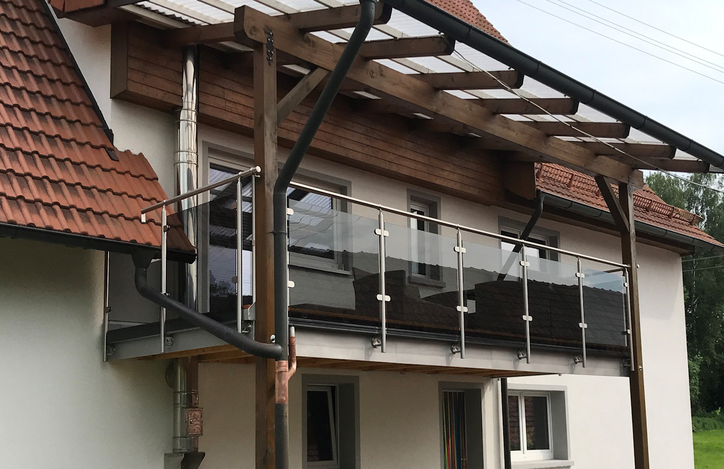 Edelstahl Balkongeländer mit Grauglas vorgesetzt montiert