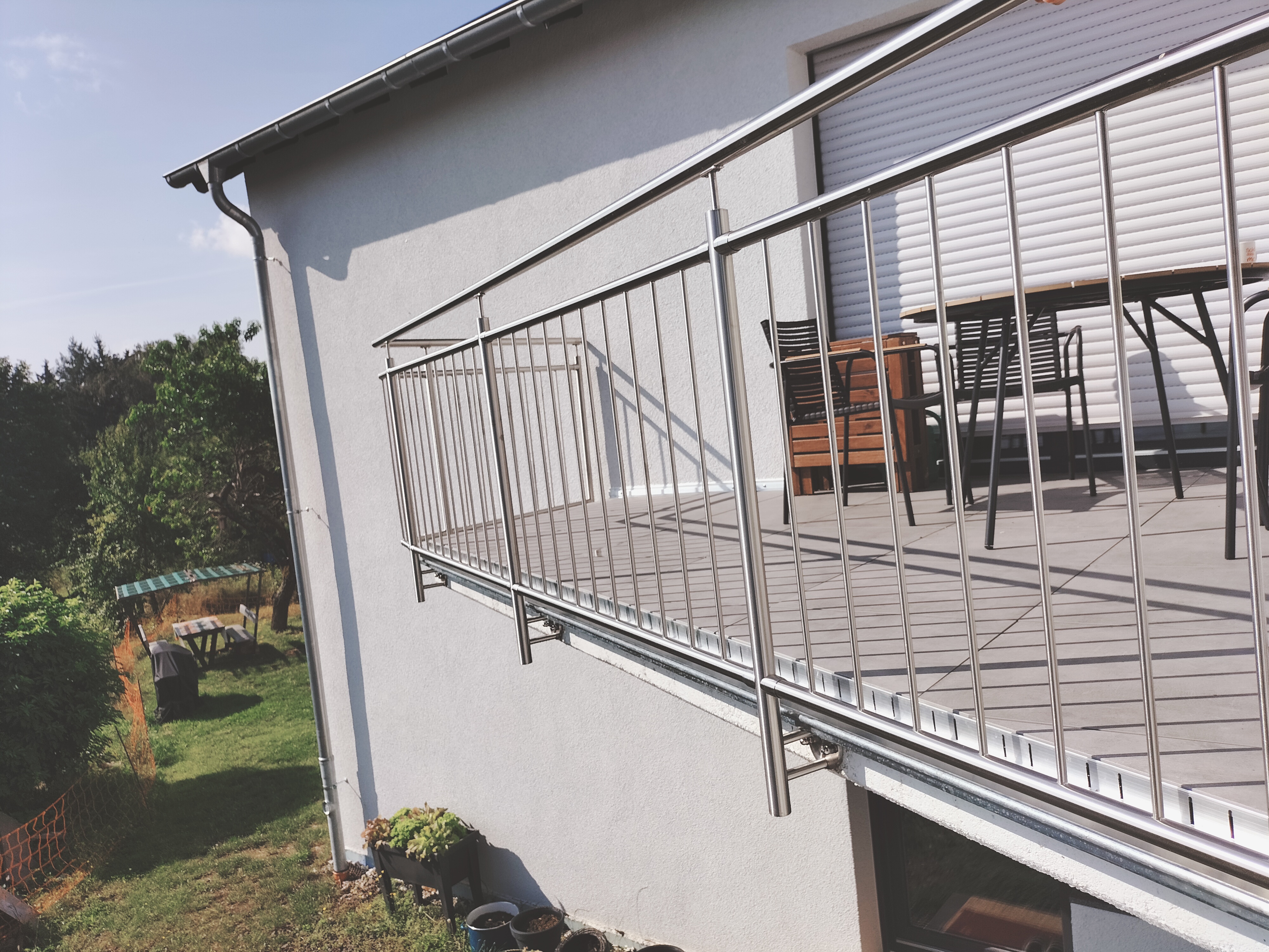 Edelstahl-Stabgeländer in vorgesetzter Montage an einer Dachterrasse mit Blick in den Garten