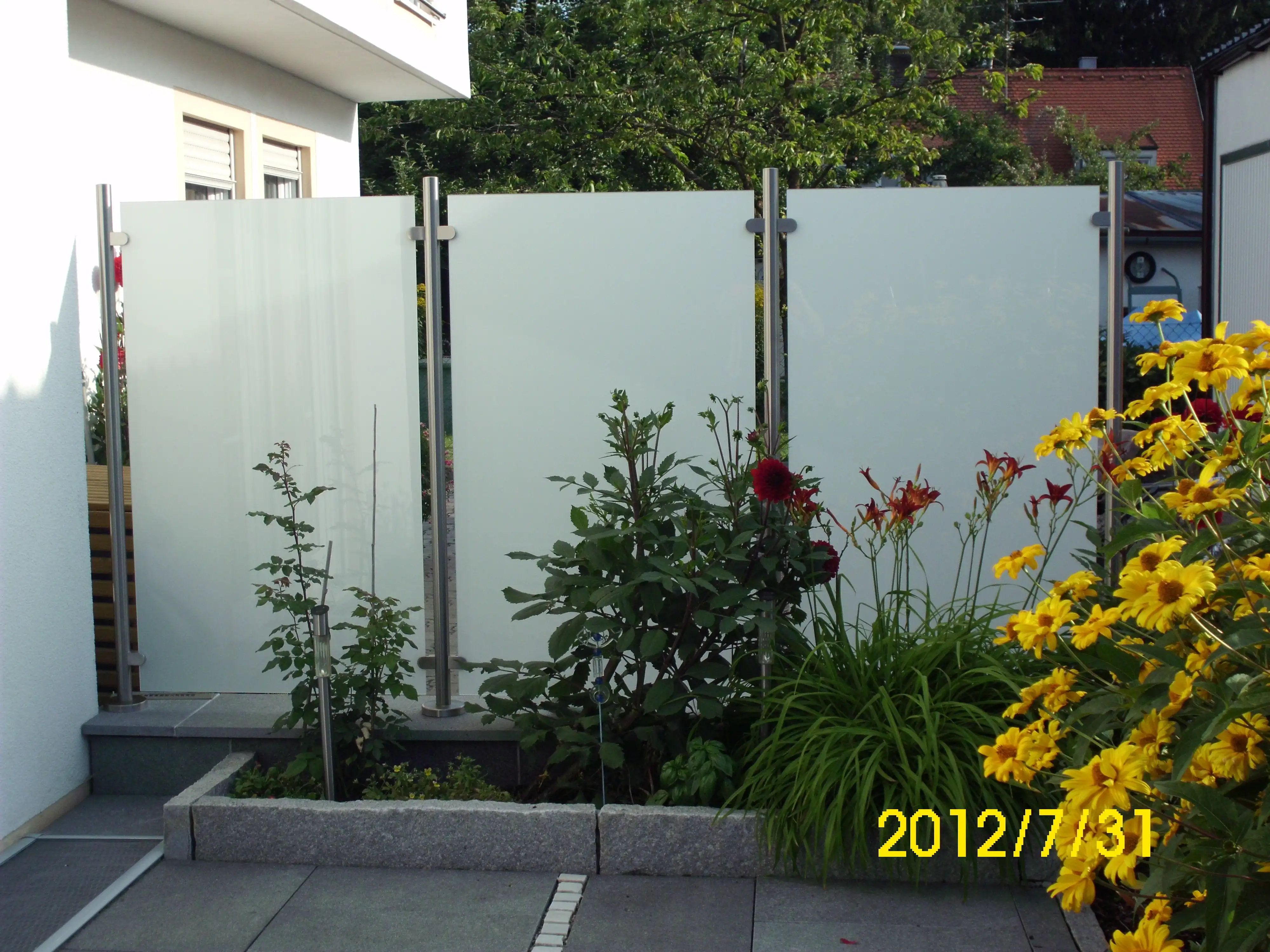 Sichtschutz aus Edelstahl und Milchglas als blickdichte Abgrenzung zum Nachbarn