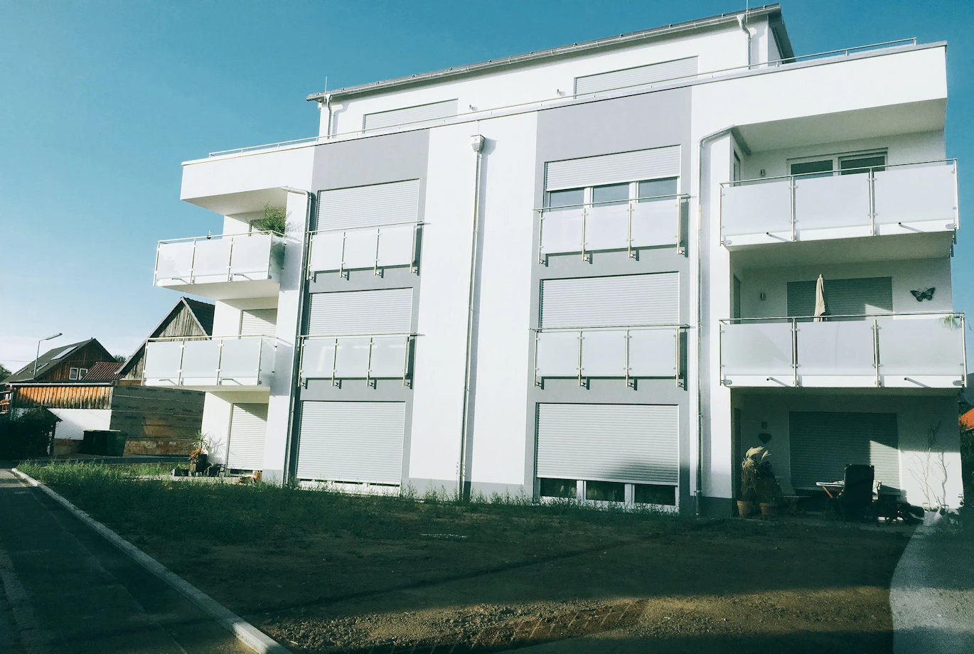 Edelstahlgeländer mit Sicherheitsglas und blickdichter Folie an einen Mehrfamilienhaus