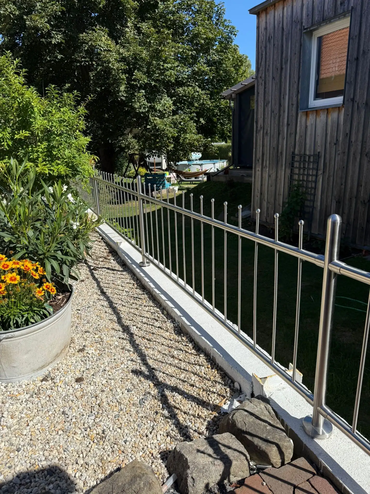 Hochwertiger Edelstahlzaun Bausatz zur Selbstmontage als Grundstücksgrenze auf einer Mauer montiert