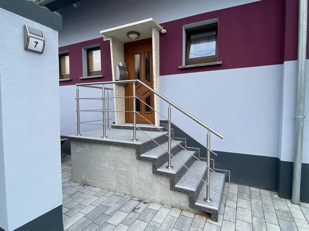 Relinggeländer mit drei Querstreben auf einer Eingangstreppe aufgesetzt montiert inklusive Wandbefestigung für Stabilität